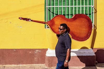 Musicien avec sa contrebasse marchant dans la rue colorée de Trinidad - Cuba