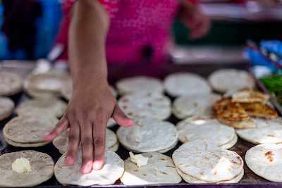 Une femme prépare des pupusas sur un marché de rue au Salvador 